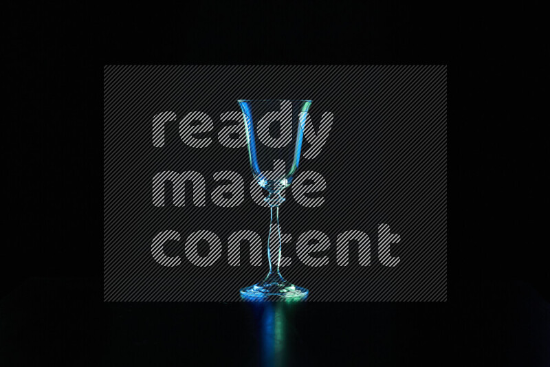 Glassware with rim light in blue and green against black background