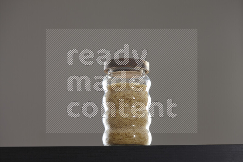 Basmati golden rice in a glass jar on black background