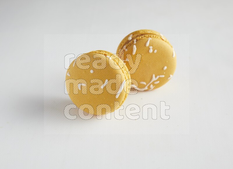 45º Shot of two Yellow Piña Colada macarons on white background