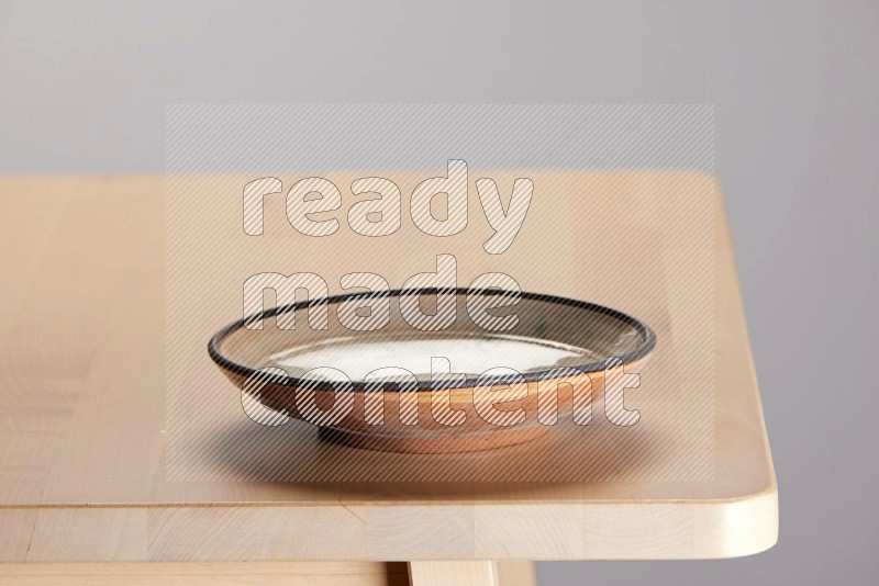 multi-colored pottery Plate on a wooden table edge