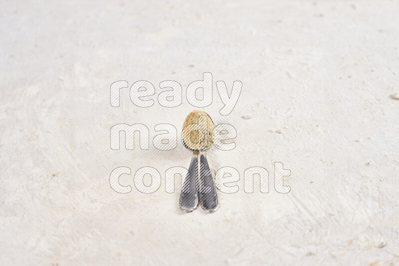 Two metal spoons full of ground ginger powder on white background