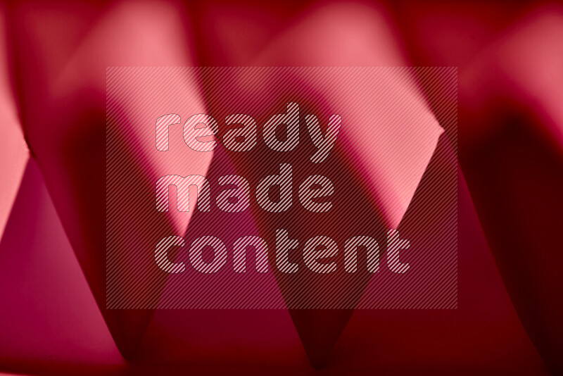 صورة مجردة مقربة تظهر طيات ورقية هندسية حادة بتدرجات اللون الأحمر