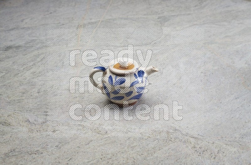 A Pottery Teapot On Grey Marble Flooring