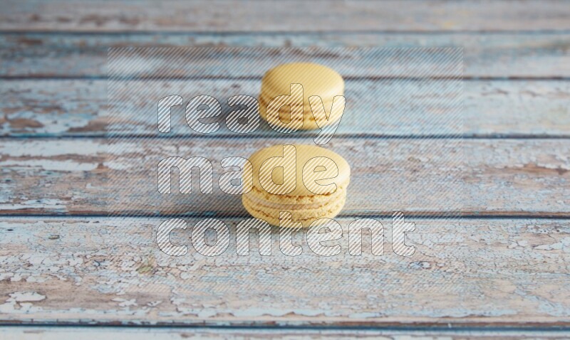 45º Shot of two Yellow Vanilla macarons on a light blue wooden background