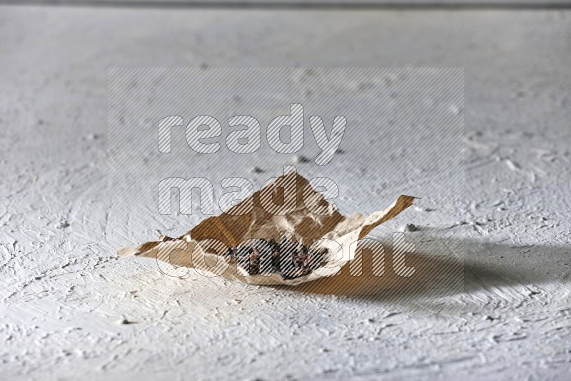 Cloves on crumpled piece of paper on a textured white flooring