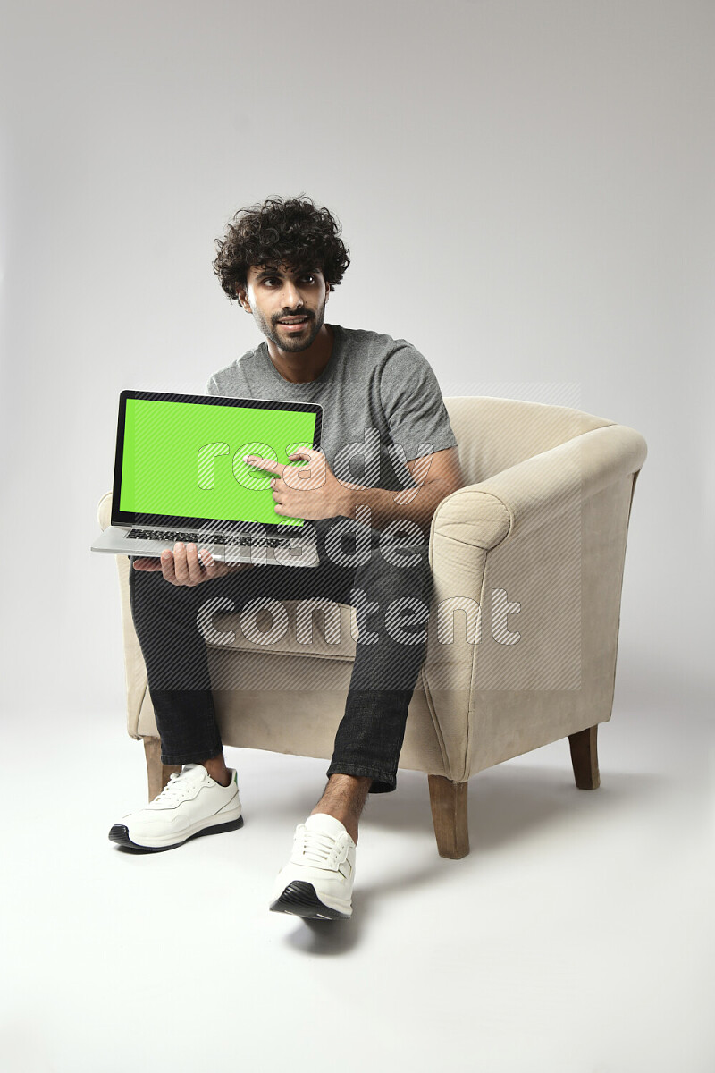 A man wearing casual sitting on a chair showing a laptop screen on white background