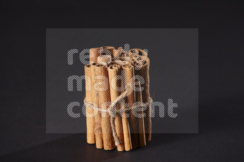 A bounded stack of cinnamon sticks on black background