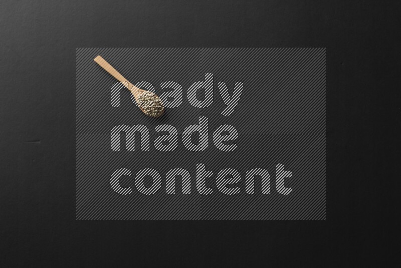 الفلفل الأسود وحبوب الخردل وحبة البركة وحب الرشاد والكمون و حبوب الكتان في معالق خشبية علي خلفية سوداء