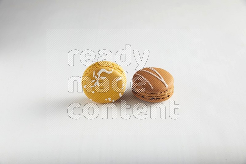 45º Shot of of two assorted Brown Irish Cream, and Yellow Piña Colada macarons on white background