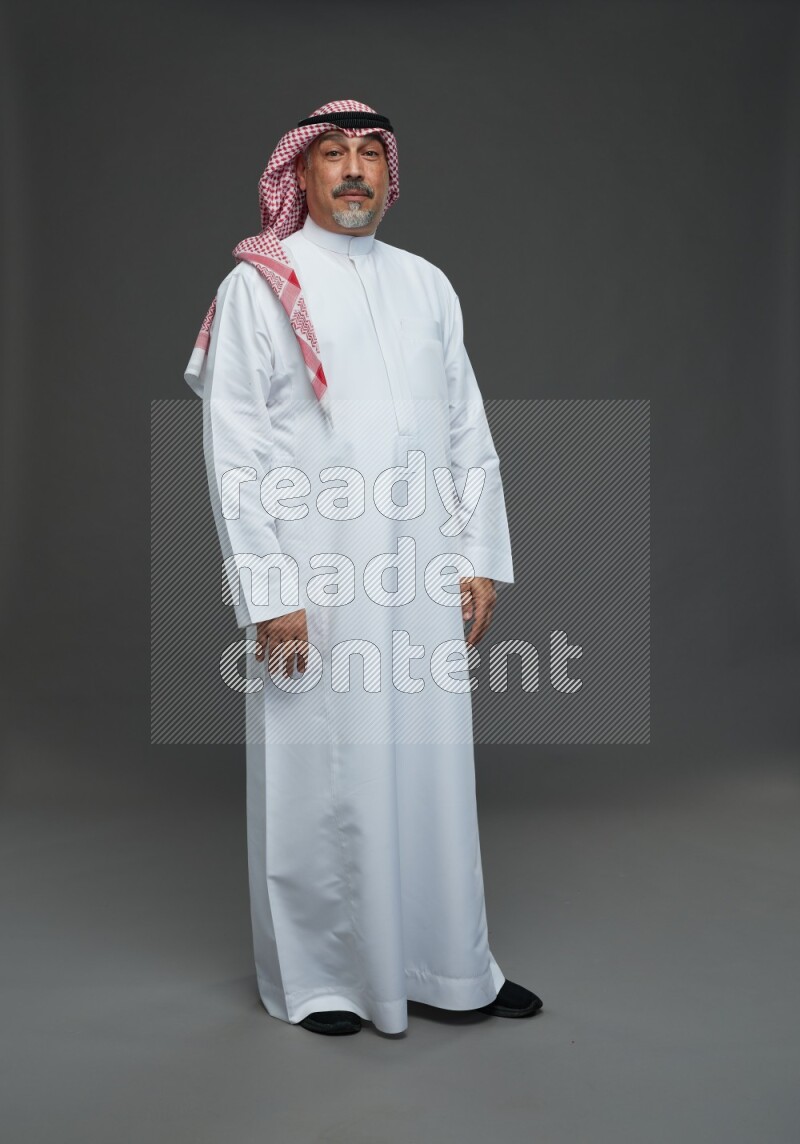 Saudi man with shomag Standing Interacting with the camera on gray background