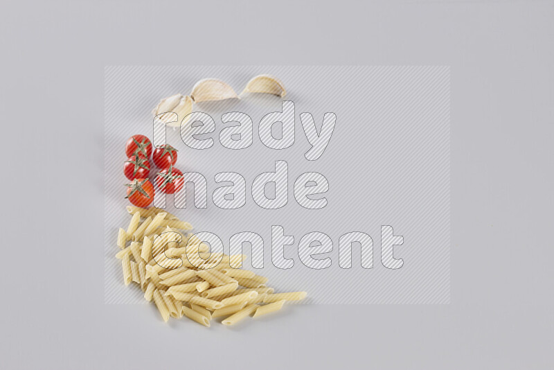 Mini penne with garlic, cherry tomatoes and wheat stalks on light grey background