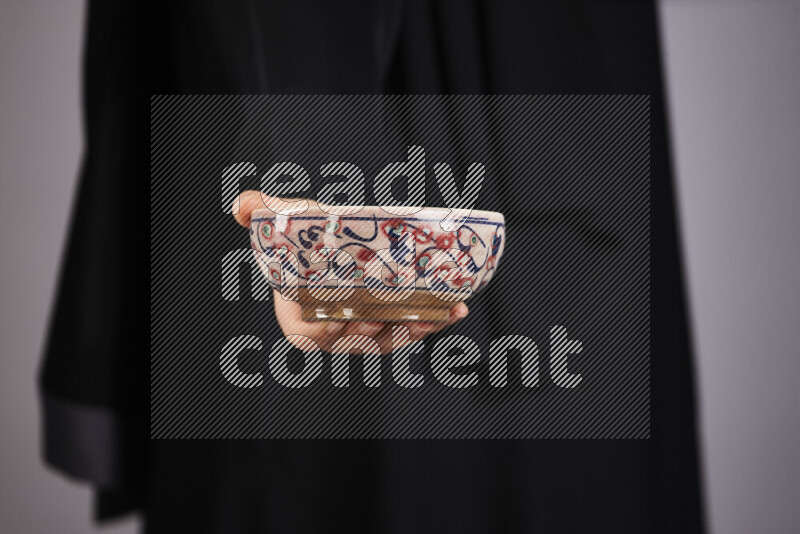 A woman in black abaya holding different pottery essentials in different positions