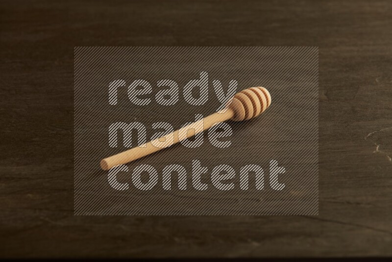 Wooden honey dipper on black slate background
