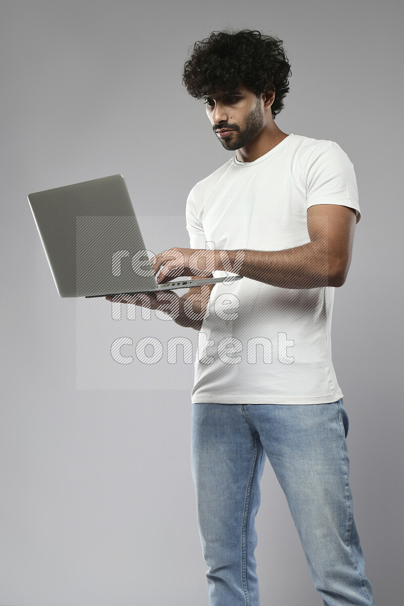 A man wearing casual standing and working on a laptop on white background