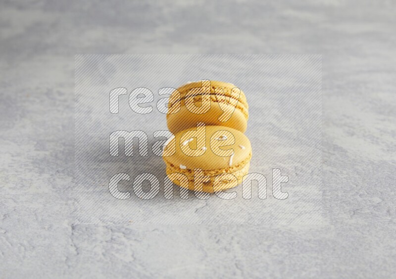 45º Shot of two Yellow Piña Colada macarons  on white  marble background