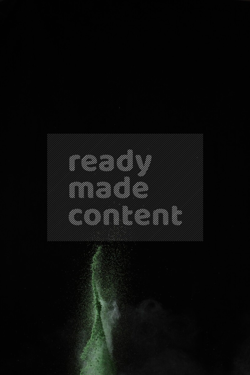 A side view of green powder explosion on black background