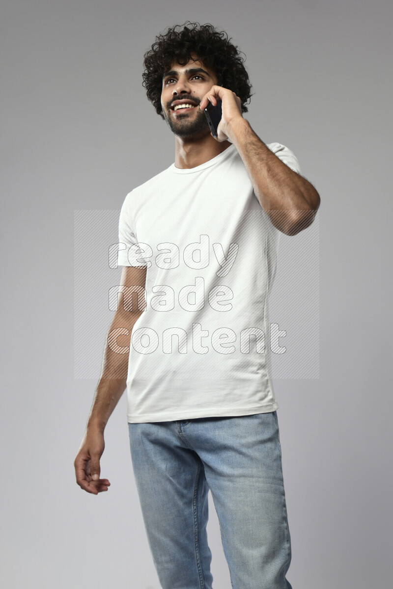 A man wearing casual standing and talking on the phone on white background