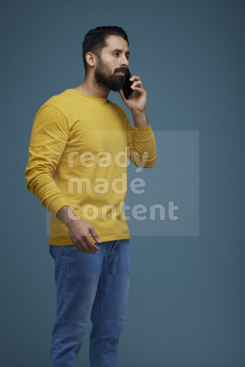 A man having a calling in a blue background wearing a yellow shirt