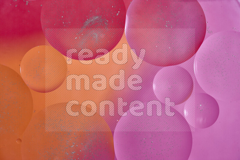 لقطات مقربة لفقاعات من الزيت على سطح الماء باللون الأحمر والبرتقالي والوردي