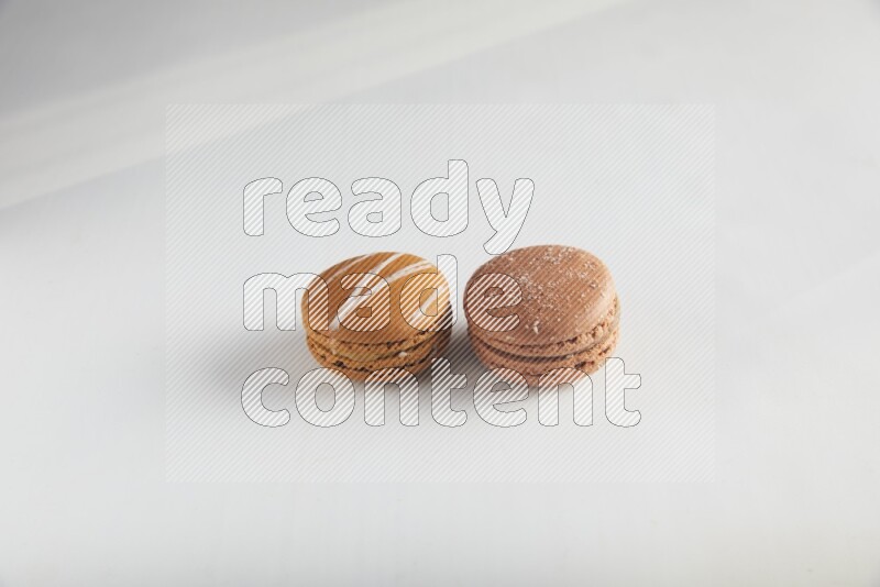 45º Shot of of two assorted Brown Irish Cream, and Brown Hazelnuts macarons on white background