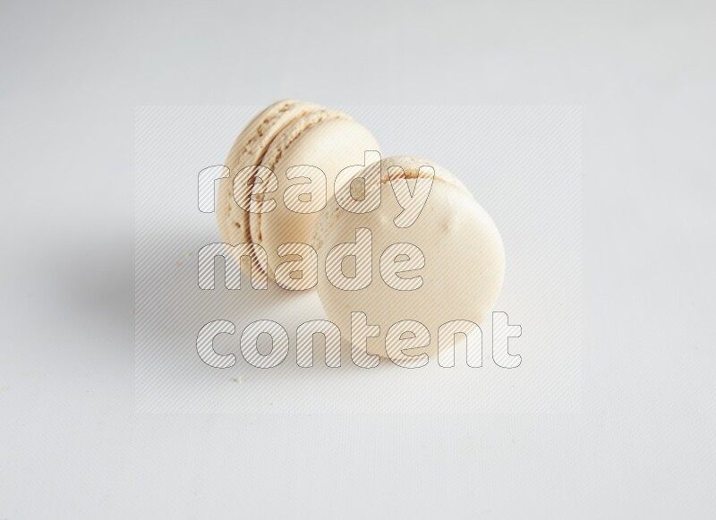 45º Shot of two White Caramel fleur de sel macarons on white background