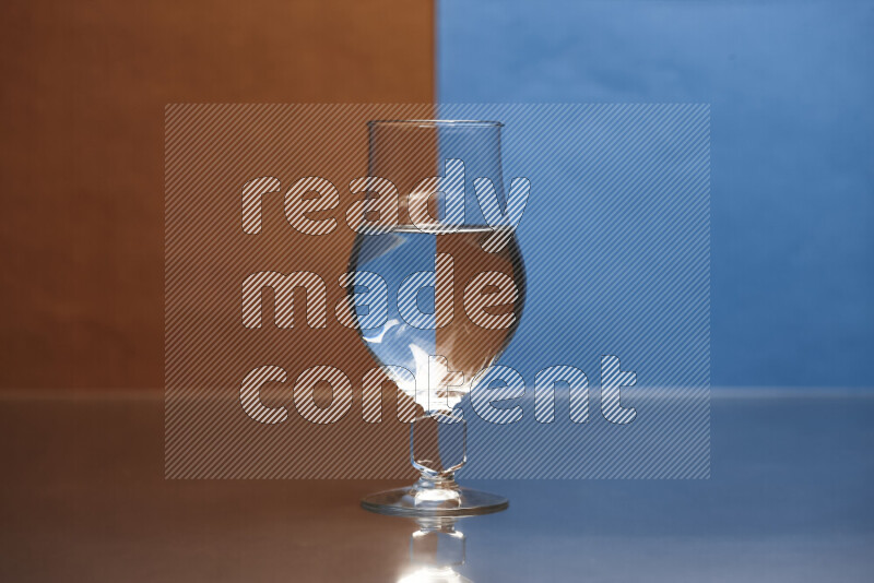 The image features a clear glassware filled with water, set against brown and blue background