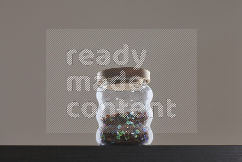 Sequins in a glass jar on black background