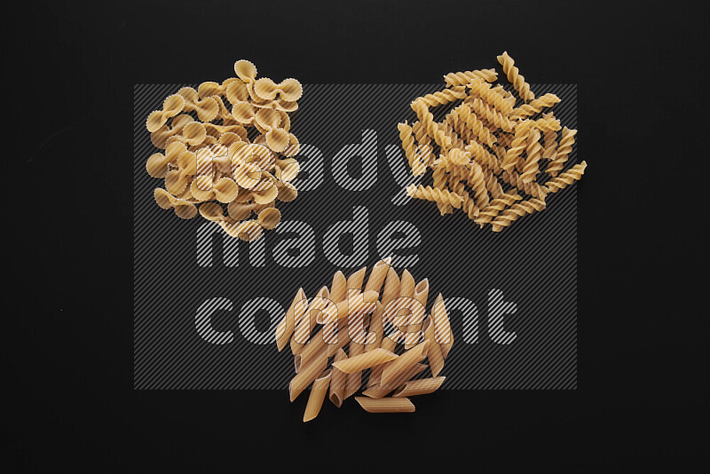 Different pasta types in bunches on black background