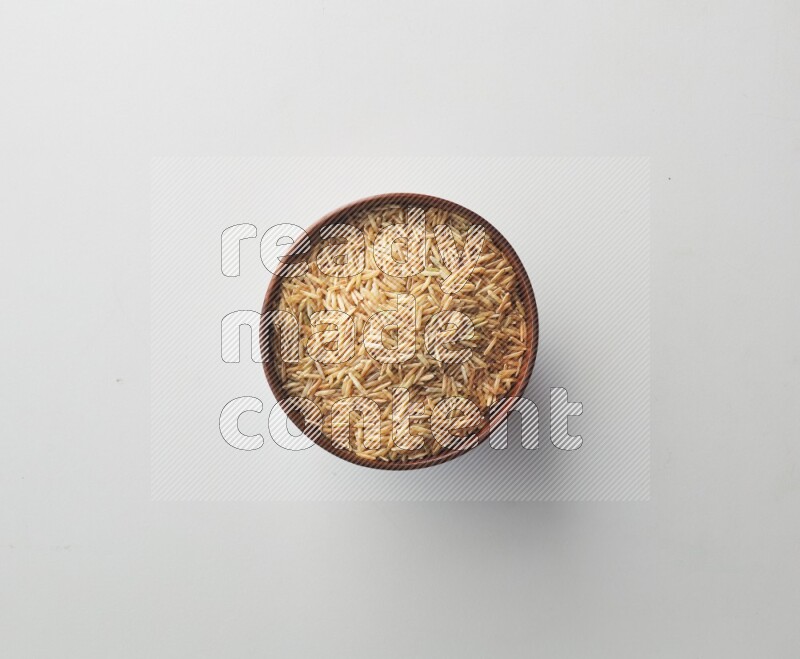 Top-view shot of long grain brown rice in a container on white background