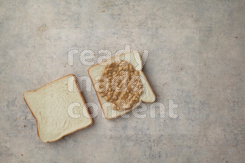 crunchy peanut butter on white toast and white toast slices on a light blue textured background