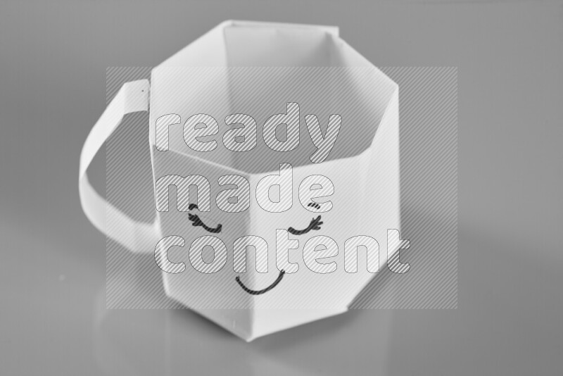 Origami cup on grey background
