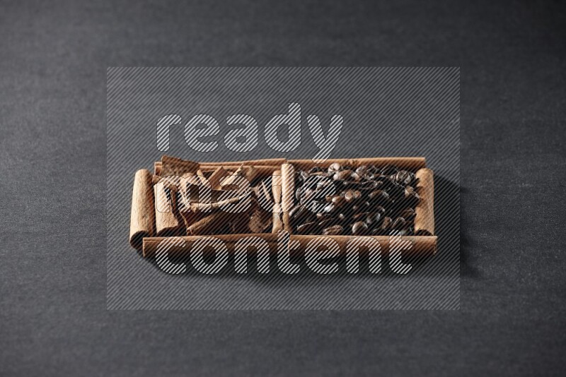 مربعان من أعواد القرفة ممتلئان بحبوب القهوة وقطع من القرفة علي خلفية سوداء