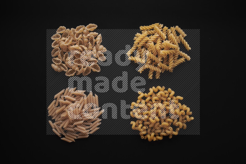 Different pasta types in bunches on black background
