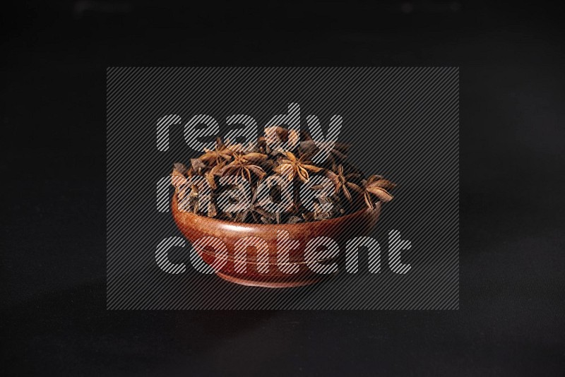 Star Anise in a wooden bowl on black flooring