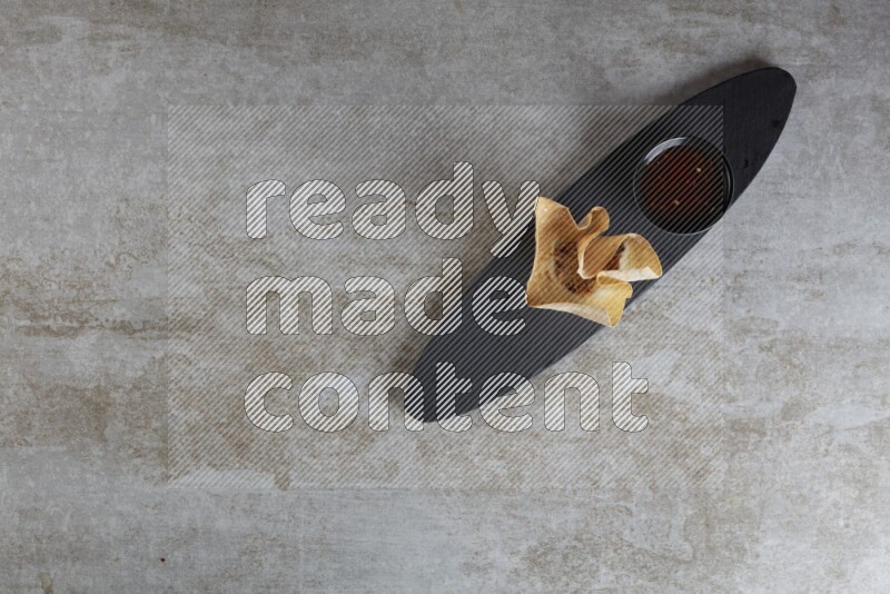 wonton cups with soy sauce ramkin on oval slate on grey textured counter top