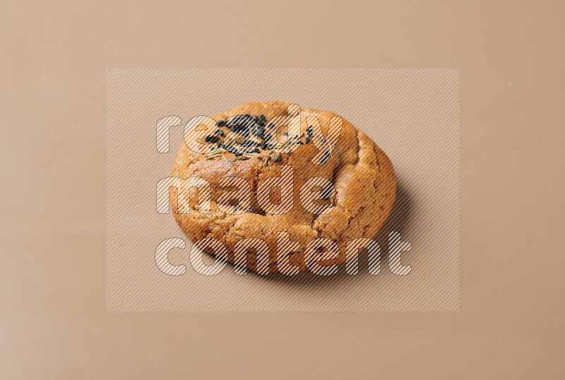 a whole Hasawi cookie with grains on a brown background