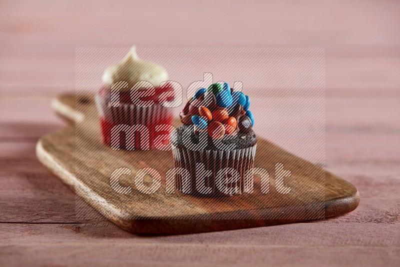 Chocolate mini cupcake topped with m&ms on a wooden board