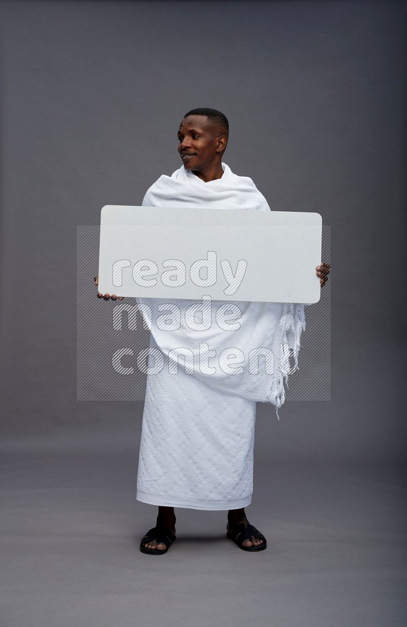 A man wearing Ehram Standing holding board sign on gray background