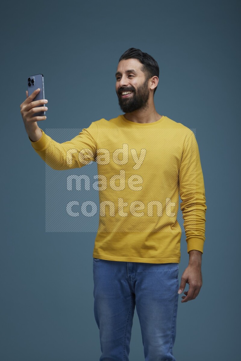 Man Taking a Selfie  in a blue background wearing a yellow shirt