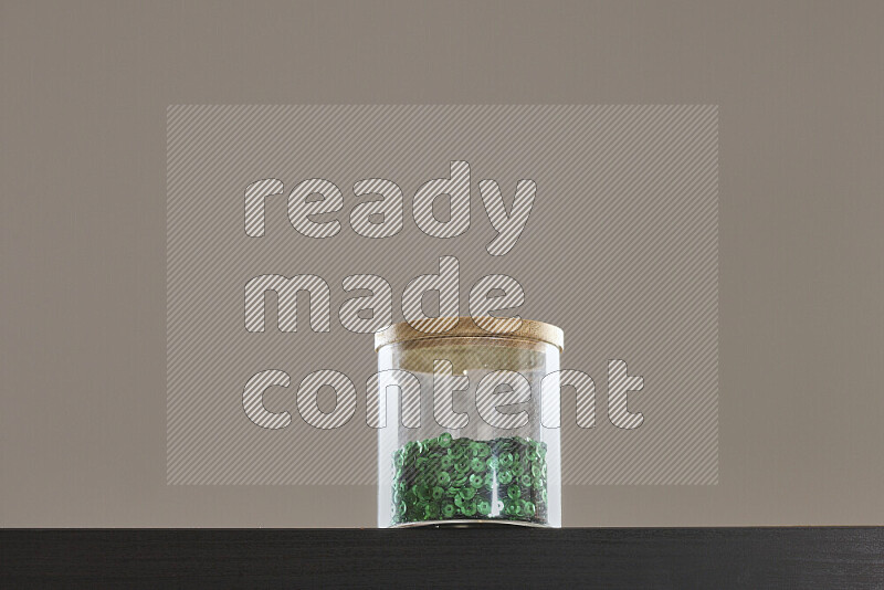 Sequins in a glass jar on black background