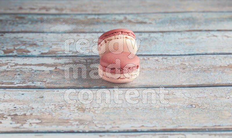 45º Shot of two Pink Litchi Raspberry macarons on light blue wooden background