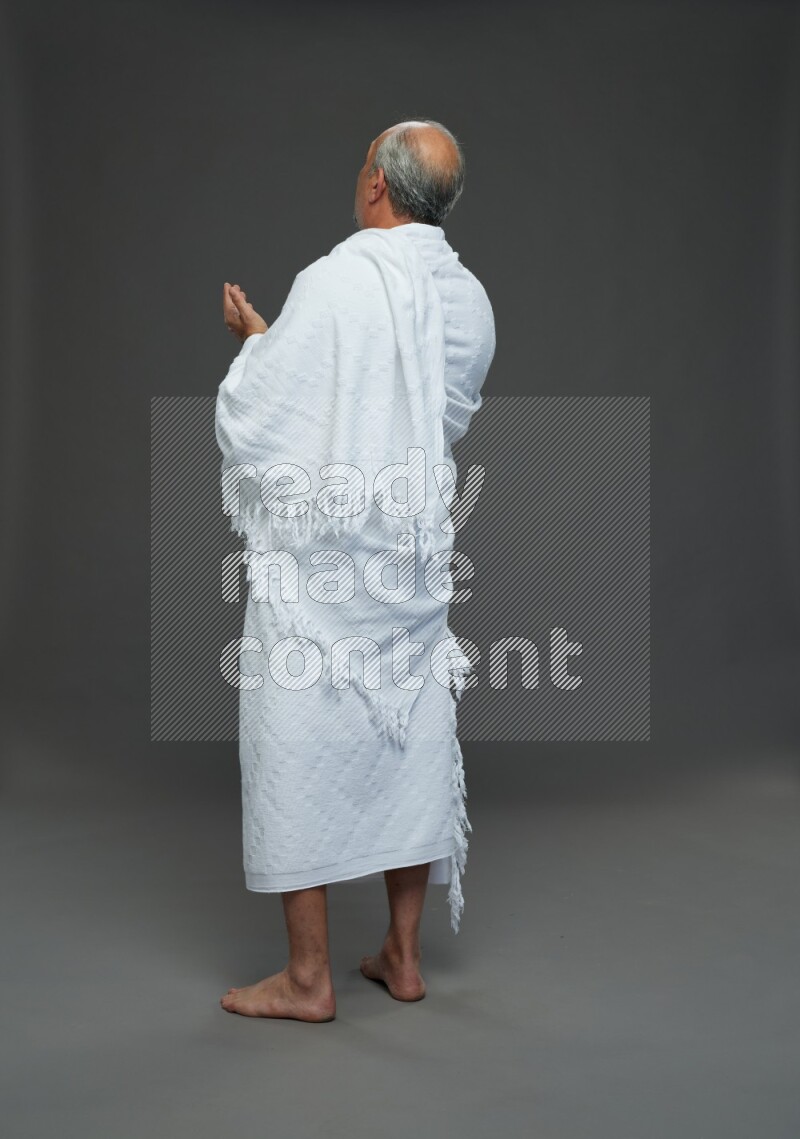 A man wearing Ehram Standing dua'a on gray background