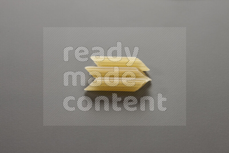 Mini penne pasta on grey background