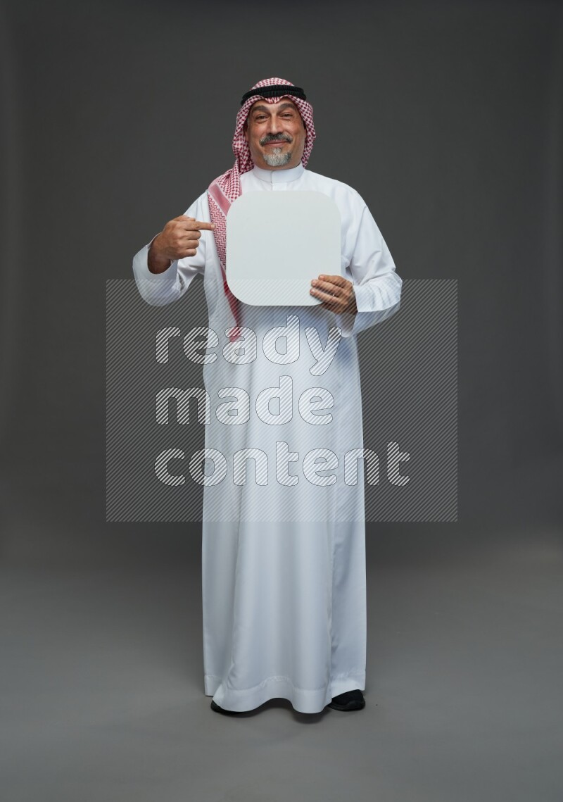 Saudi man with shomag Standing holding social media sing on gray background