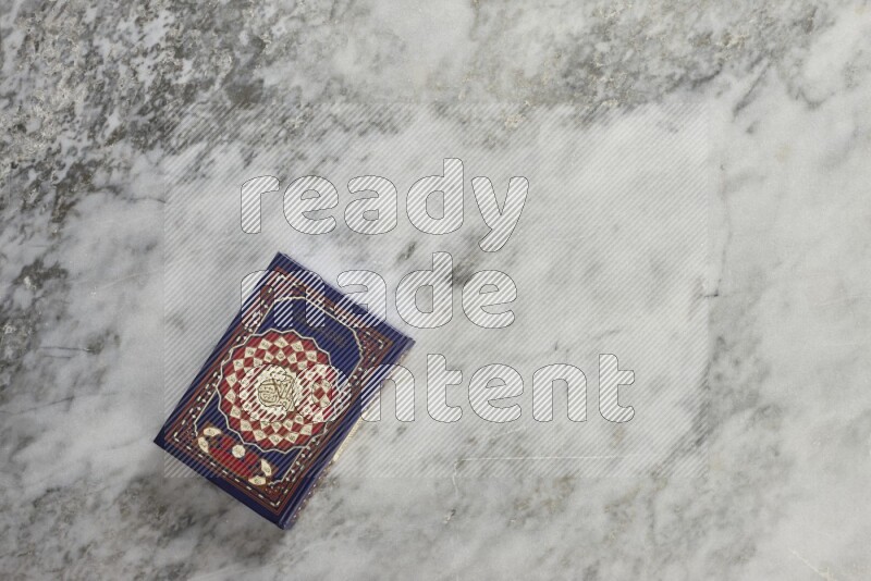 Quran with a prayer beads on grey marble background