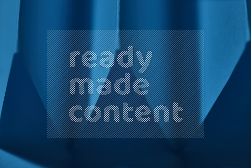 صورة مجردة مقربة تظهر طيات ورقية هندسية حادة بتدرجات اللون الأزرق