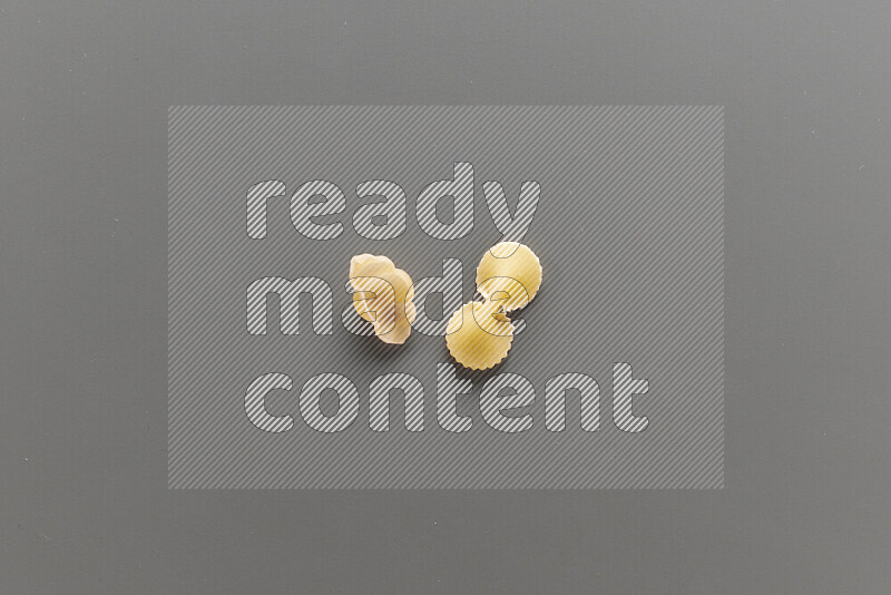 Snails pasta with other types of pasta on grey background