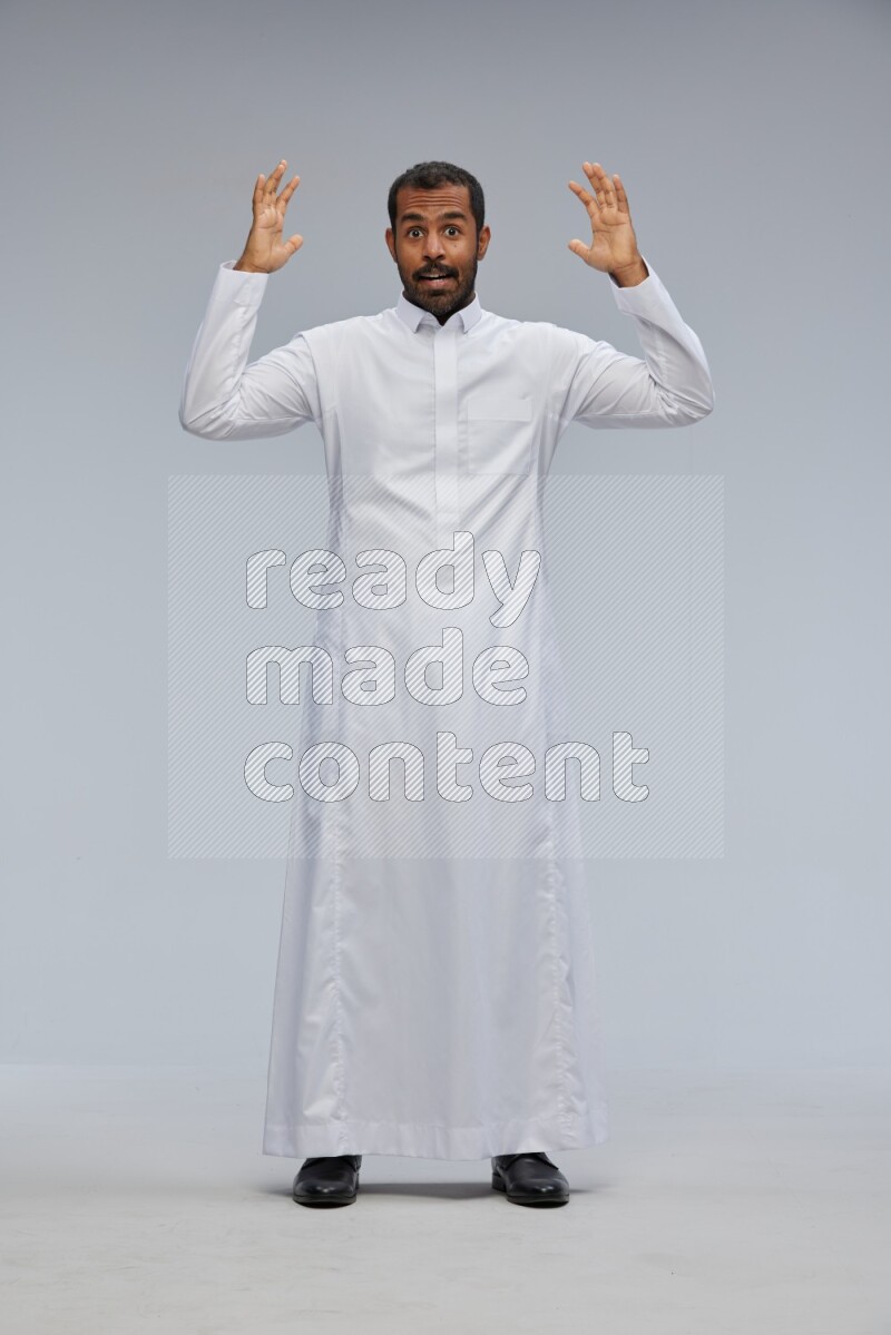 Saudi man Wearing Thob standing interacting with the camera on Gray background