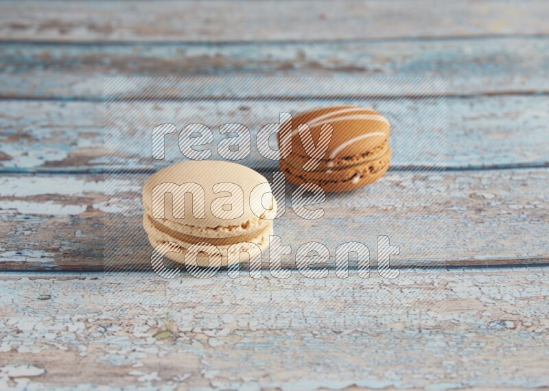 45º Shot of of two assorted Brown Irish Cream, and White Caramel fleur de sel macarons on light blue background