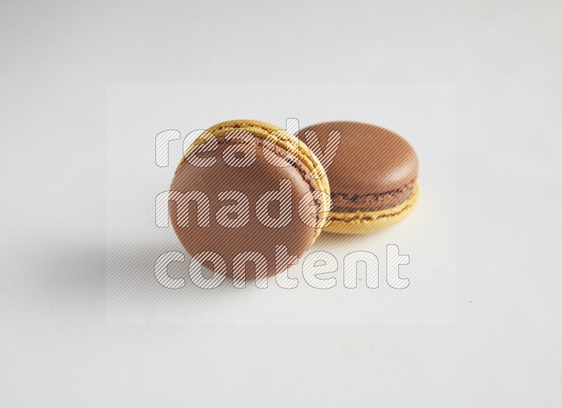 45º Shot of two Yellow and Brown Chai Latte macarons on white background